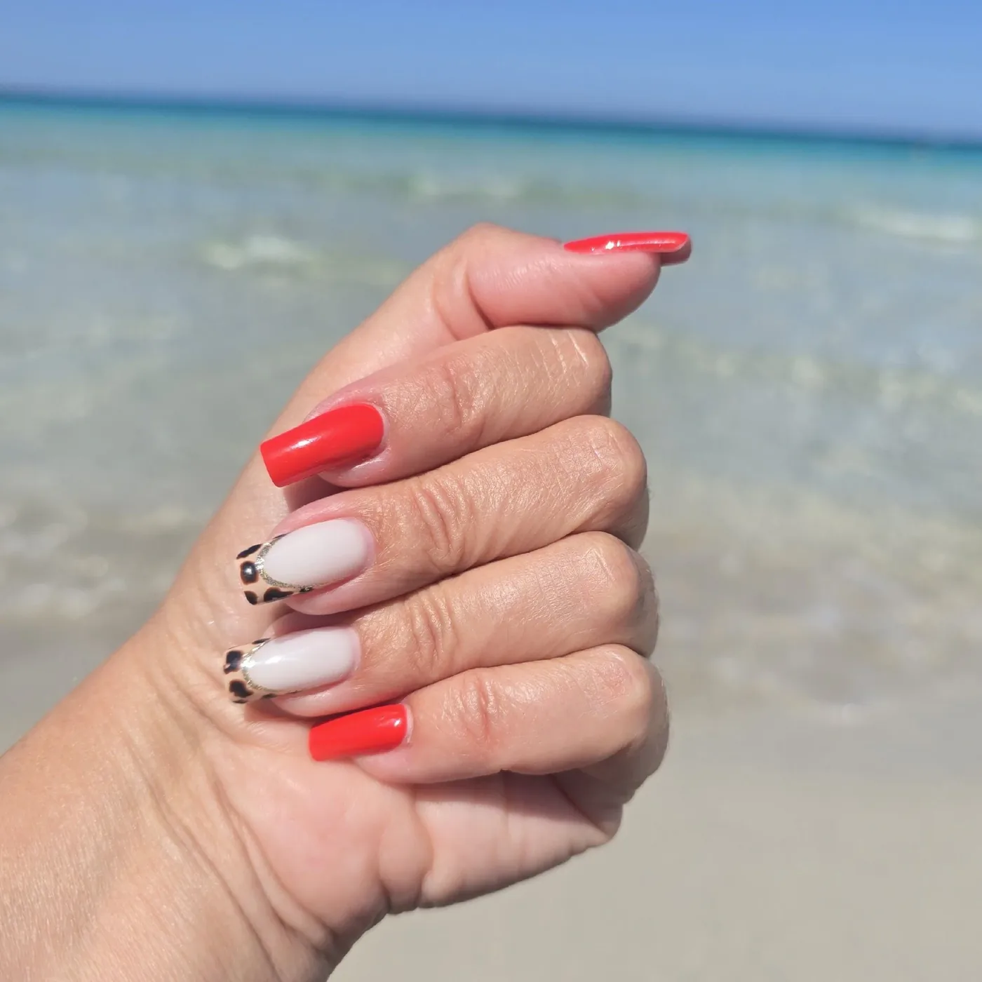 Manicura coral con francesa de leopardo en la playa de Elviria